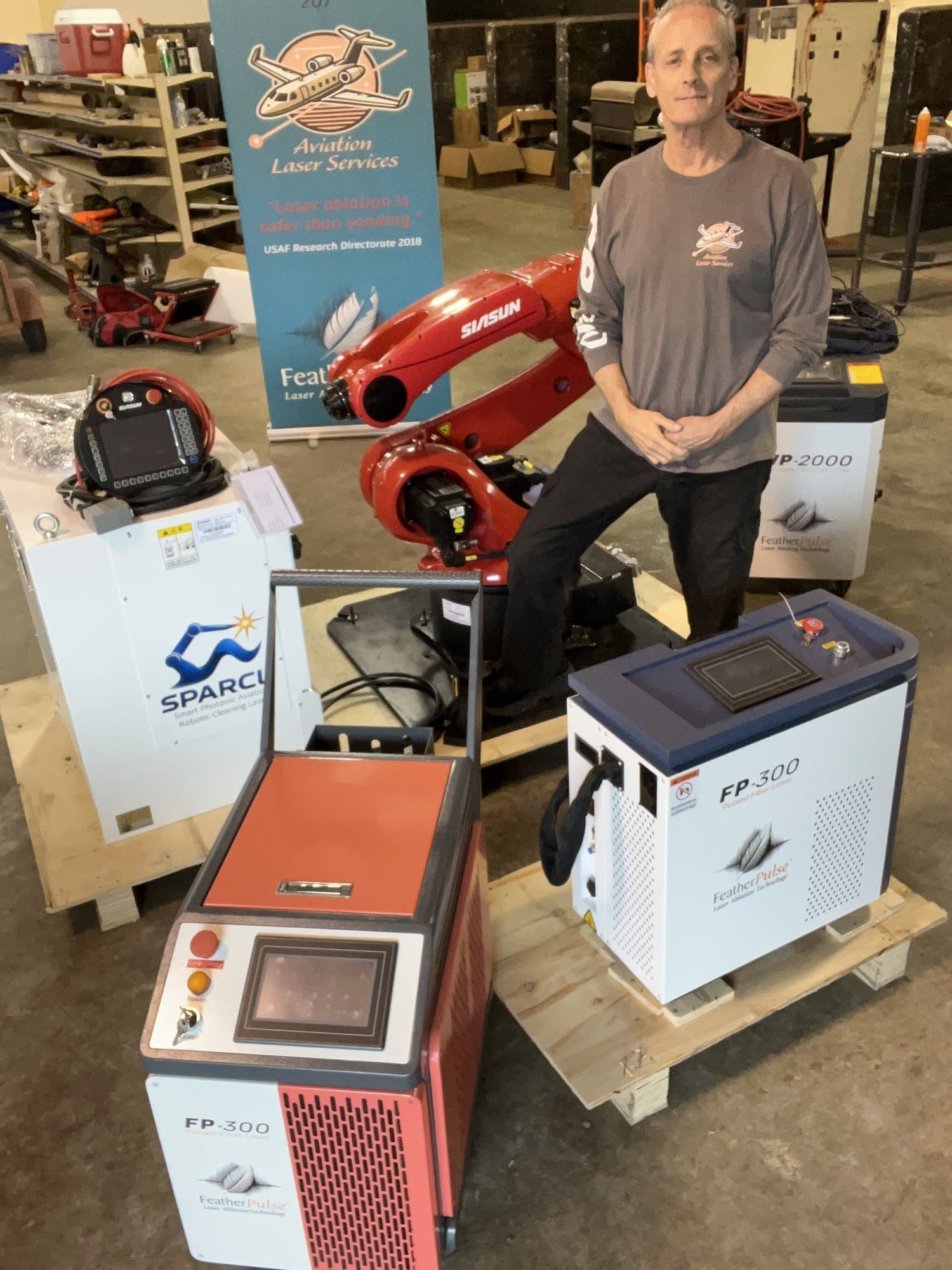La gama FeatherPulse al completo: los equipos FP-300 y XP-2000, el brazo robótico SPARCL y el expositor de Aviation Laser Services.